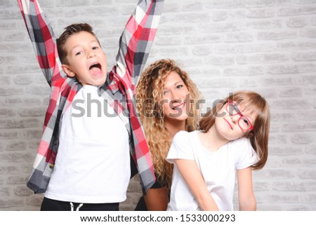 Portrait of happy boy and two girls. Cute brother and sister isolated on white brick will background. Funny couple children laughing with a perfect smile