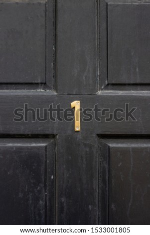 House number one on a square black wooden front door