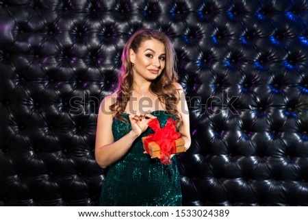 Beautiful happy woman with gift box at celebration party on the dark background. Birthday or New Year eve Sale celebrating concept