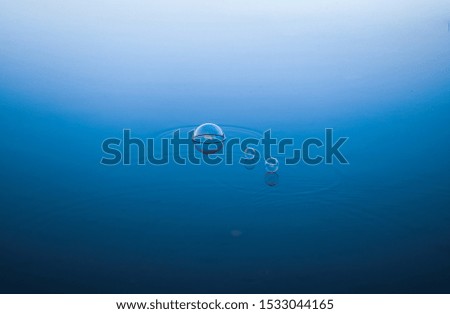 Soap bubbles floating on the blue lake water surface. Empty space for text. 