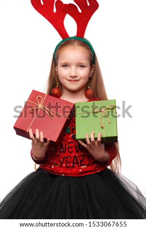 Beautiful little girl in a New Year's image with boxes of gifts in hands and deer horns on her head. Photo taken in the studio.
