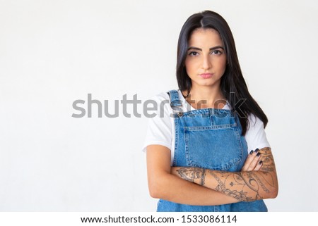 Serious young brunette with crossed arms. Thoughtful brunette lady posing on light background. Female beauty concept