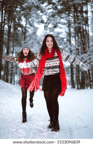 Two young teenage hipster girl friends together.Close up fashion portrait of two sisters hugs and having fun winter time,wearing sweater,best friends couple outdoors, snowy weather
