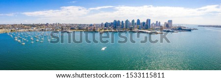 Amazing panoramic view of the San Diego downtown by the harbour with many skyscrapers and huge aircraft carrier docked by the pier.