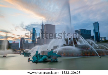 Famous buckingham fountain in Chicago park outside downtown with beautiful sunset skyline in background.