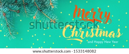 Seasonal banner with border of fluffy green fir branches and gold confetti stars sparse on trendy mint background. Modern colored holiday design. Merry Christmas and Happy New Year text