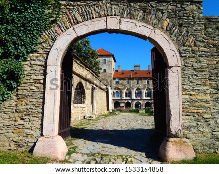 Sunny picture of the medieval castle walls of the the Hungarian town Tata, the castle is captured through the gate of the gray rocky wall