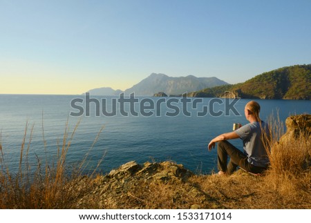 A man with cup of coffee meets sunrise on the seashore, Turkiye, Lykia
