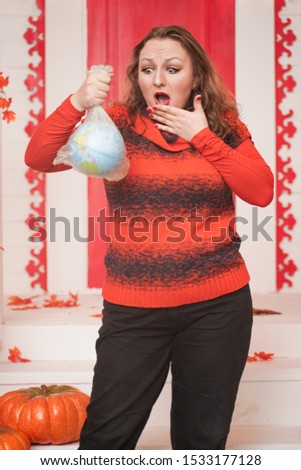 an emotional adult woman holds a planet in a plastic bag in her hands and shows irresponsible excessive consumer plastic