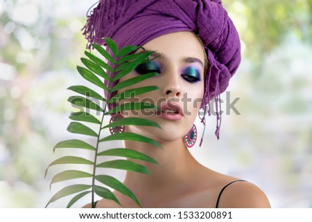 Beautiful young woman with fashion makeup   and turban with leaf. Portrait of beauty fashion model with professional make up and long eyelashes. Beauty and skincare.