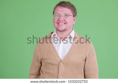 Portrait of happy overweight bearded man with eyeglasses thinking
