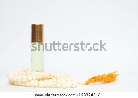 A high key picture of attar oil and "tasbeeh" or prayer beads with copy space. It is Muslim friendship concept.