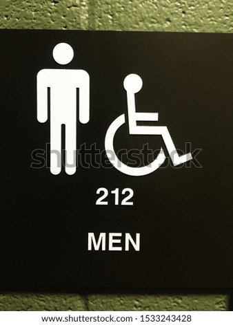 Men’s restroom sign on green cinder block background