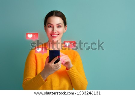 Young woman is using smartphone. Happy girl on teal background. Social media concept. Heart icons.                               