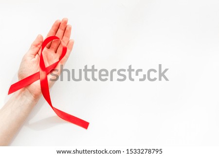 AIDS disease symbol. Red ribbon in hands on white background top view copy space