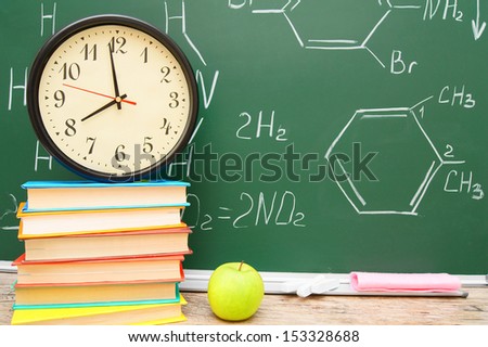 Watch on books, and an apple against a school board (chemical formulas).