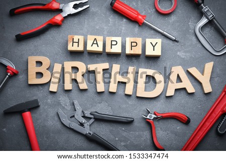 Tools and words HAPPY BIRTHDAY on grey stone background, flat lay
