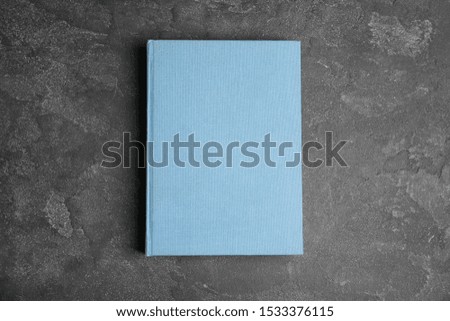 Hardcover book on grey stone table, top view. Space for text