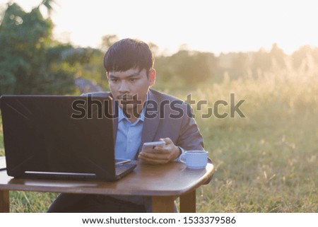 Asian businessmen wear blue suits and use notebook computers in the office in the morning. He showed signs of being happy with a successful deal while sitting in his office.
