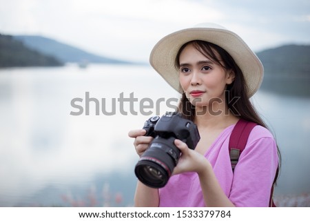 Asian woman photography with camera, hat and backpack holding camera travel in holiday on river and mountain background.