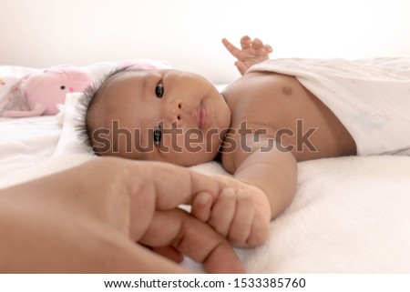 Newborn baby holding father's finger While sleeping comfortably on the white mattress During bedtime, the child's brain will work. To enhance Memory-boosting and learning-building skills
