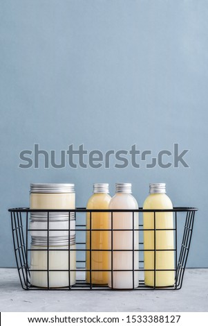 Bottles with spa cosmetic products in  metal basket on blue background. Beauty salon treatments concept.