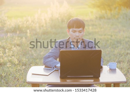Asian businessmen wear blue suits and use notebook computers in the office in the morning. He showed signs of being happy with a successful deal while sitting in his office.