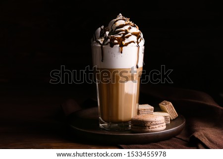 Glass of tasty frappe coffee with sweets on wooden table Royalty-Free Stock Photo #1533455978