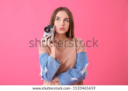 Beautiful young woman with photo camera on color background