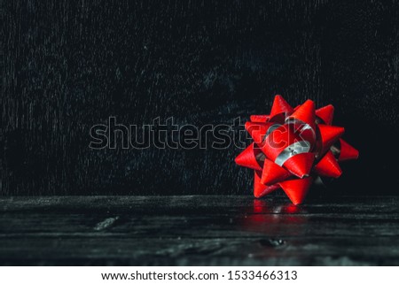 Red gift bow on an old fashioned country table. Selective focus. Horizontal, Christmas concept, Red ribbon on paper gift wrap.