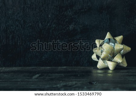 Golden gift bow on an old fashioned country table. Selective focus. Horizontal, Christmas concept, Golden ribbon on paper gift wrap.