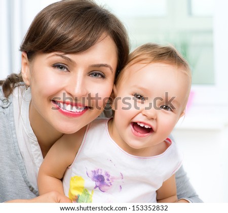 Mother and Baby kissing and hugging at Home. Happy Smiling Family Portrait. Mom and Her Child Having Fun together