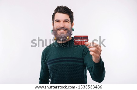 Portrait of young man with white beard showing red credit card