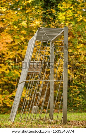 Iron football goal on a public football field with grass in front of beautiful yellow autumn trees in golden October in Germany