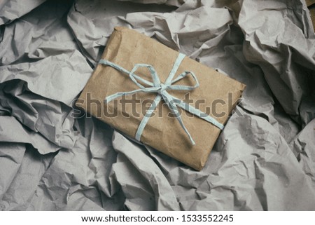 Soft pouch wrapped in craft paper and tie blue cord. Crumpled paper background texture. Delivery service. Online shopping.	