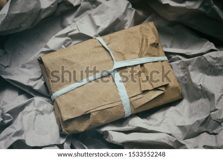 Soft pouch wrapped in craft paper and tie blue cord. Crumpled paper background texture. Delivery service. Online shopping.	