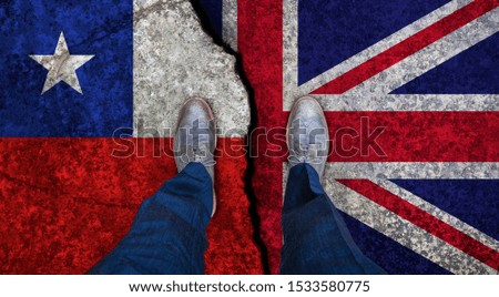 Business man stands on cracked flag of UK and Chile. Political concept