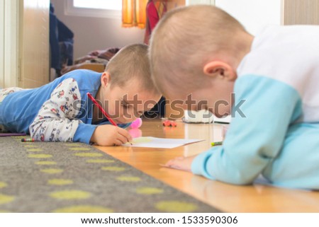 Cute little boys drawing a story with colorful pens and crayons at home. Selective focus.