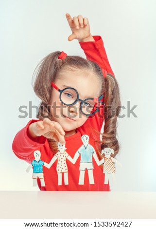 beautiful cute little girl holding paper cut out of people. International family day concept. Paper cut figures of happy family.