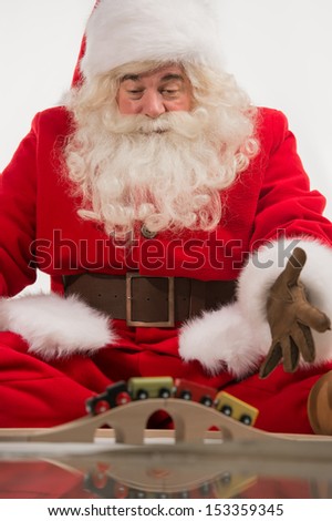 Hilarious and funny Santa Claus sitting and playing with toys on a white background