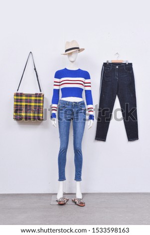 female striped dress in blue jeans trousers,hat and,shoes on full mannequin with stripes handbag, black jeans on gray background
