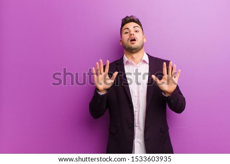 young hispanic man feeling stupefied and scared, fearing something frightening, with hands open up front saying stay away Royalty-Free Stock Photo #1533603935