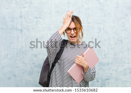 young student woman raising palm to forehead thinking oops, after making a stupid mistake or remembering, feeling dumb against grunge wall background