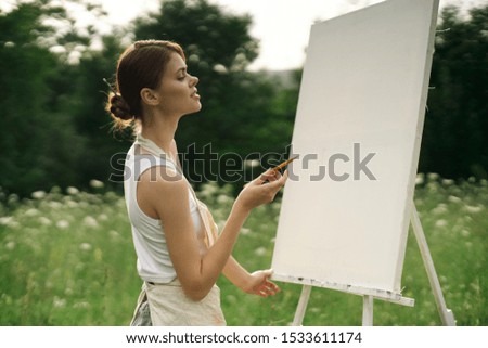 stylish young woman working behind a painting easel