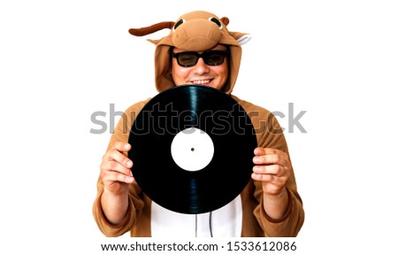 Man in cosplay costume of a cow with gramophone record isolated on white background. Guy in the animal pyjamas sleepwear. Funny photo with party ideas. Disco retro music.