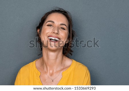 Portrait of mature woman laughing against grey background. Successful middle aged woman in casual with toothy smile looking at camera. Cheerful happy beautiful latin lady smiling with copy space. Royalty-Free Stock Photo #1533669293