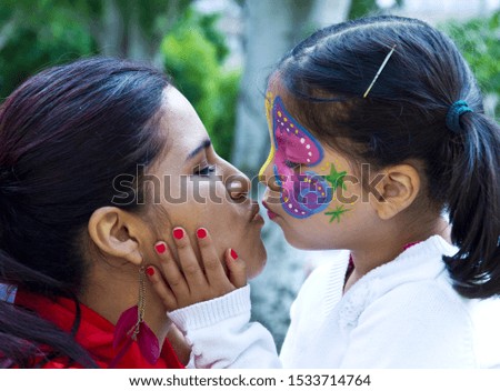 Little Girl painted face kissing her mother in the fair