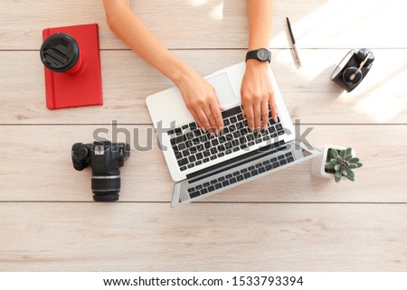 Young female photographer working on laptop at table