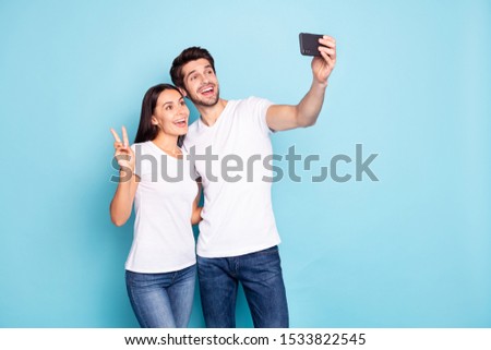 Portrait of his he her she nice attractive lovely funny glad excited cheerful cheery couple hugging making selfie showing v-sign isolated on bright vivid shine vibrant blue turquoise background