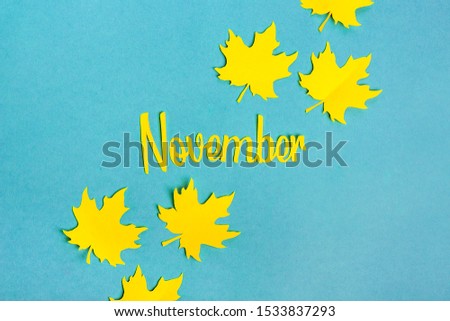 autumn leaves cut out of yellow paper, word november on blue background Hello autumn, september, october, november concept Top view Flat lay